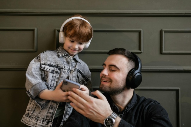 Vater und Kind hören gemeinsam Musik auf dem Smartphone.