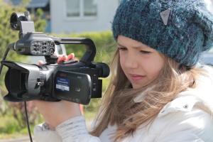Mädchen mit Mütze filmt mit einer Videokamera.