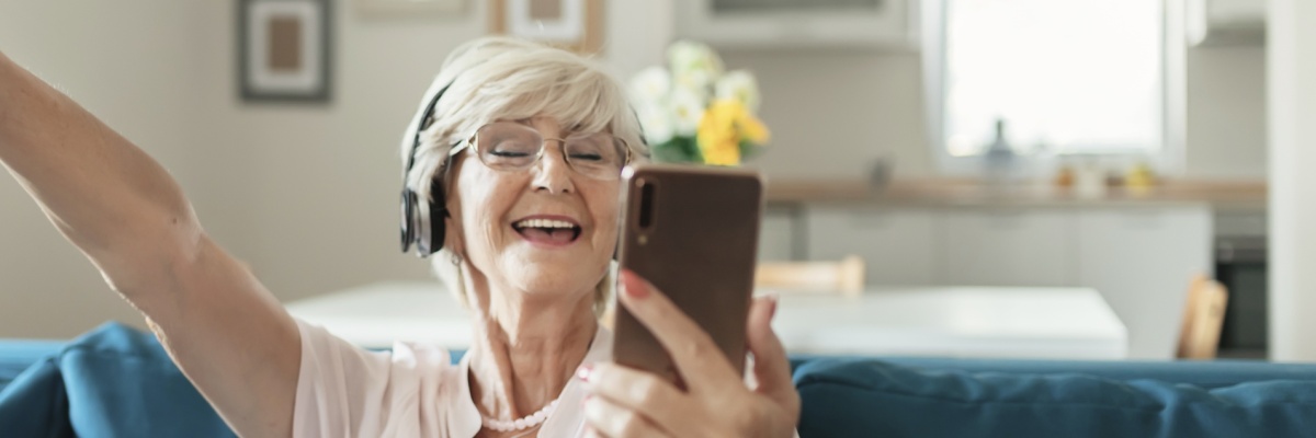 Stimmungsbild: Grauhaarige, fröhliche Frau mit Handy in der Hand
